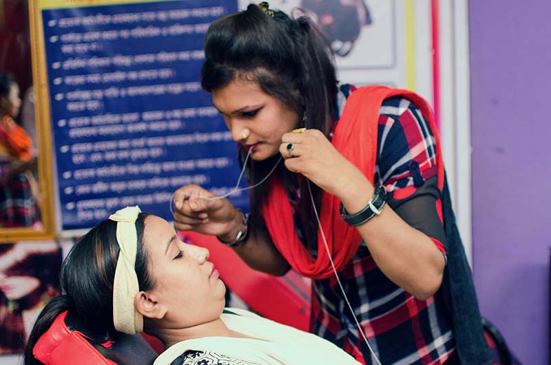 BRAC program participant Shabnoor learning a trade hands-on with a customer in a beauty salon. 