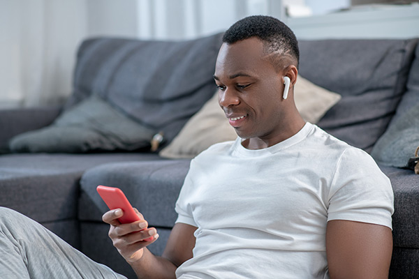 Man looking at phone with headphones in ears