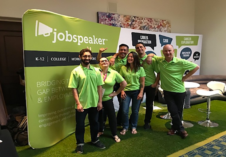People posing and smiling in front of a Jobspeaker banner