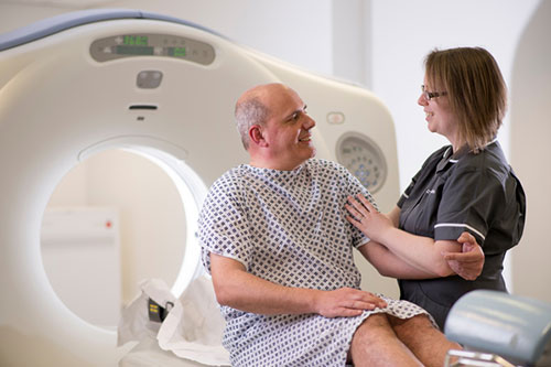 Tech assisting man to get in MRI machine