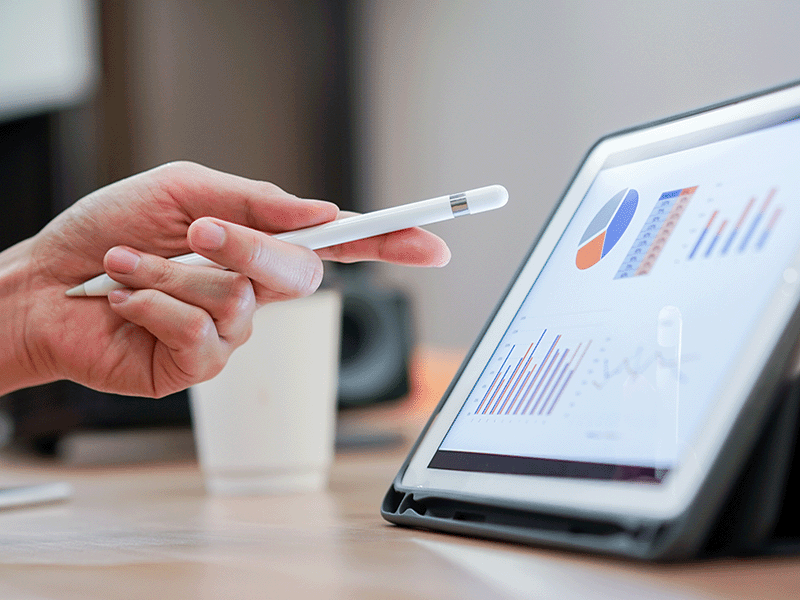 Hand holding a pen, pointing at a tablet with Tableau