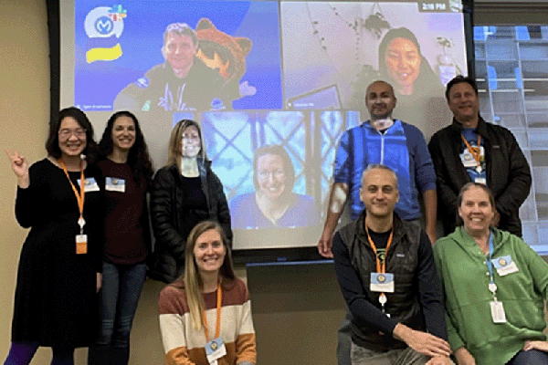 8 members of the Grants Content Kit team posing for a photo in-front of screen.