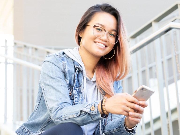 Woman smiling and working on a cell phone